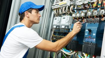 electrician with electric test screwdriver checking voltage of switching electric actuator equipment in fuse box