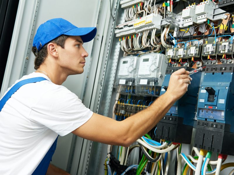 electrician with electric test screwdriver checking voltage of switching electric actuator equipment in fuse box